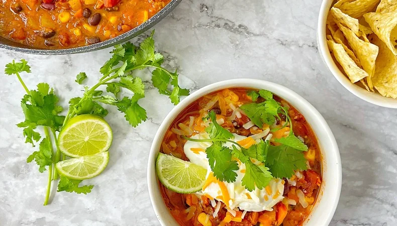 A bowl of bean chilli with lime and fresh coriander