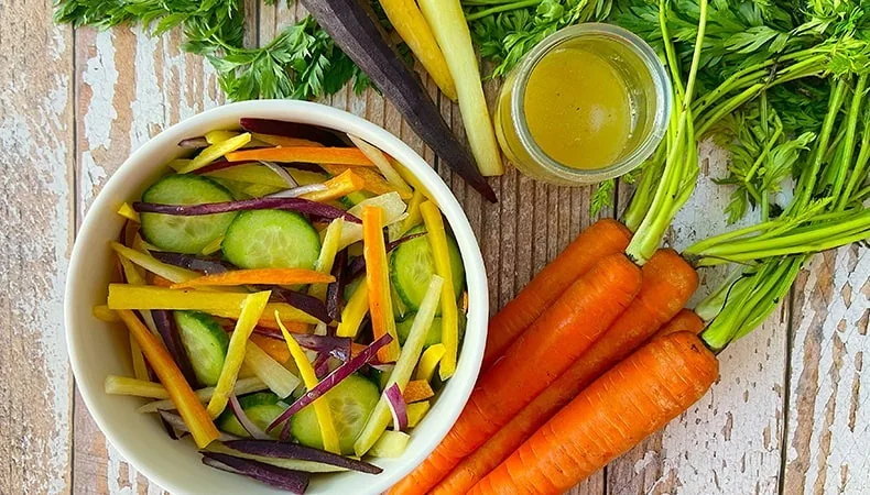 Carrot and cucumber salad beside fresh vegetables