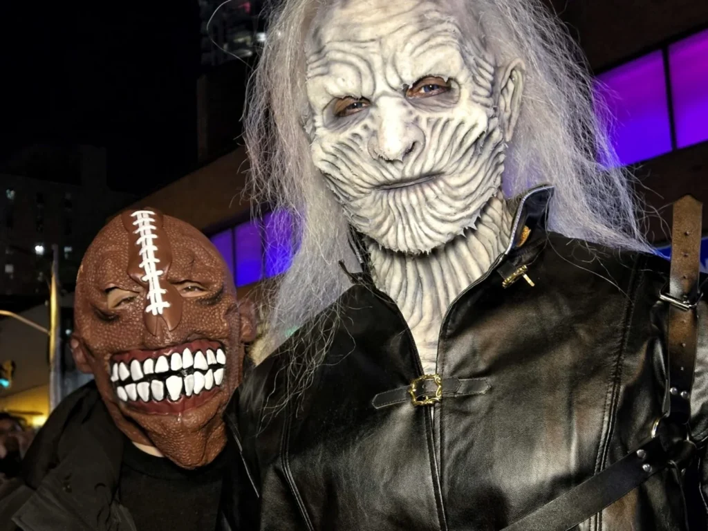 Two visitors wearing horror masks during the Village Halloween celebration