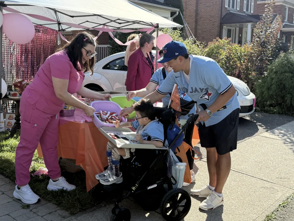 A child in a wheelchair collecting treats from a table at ground level