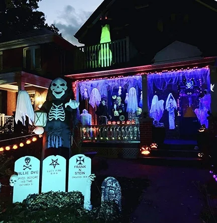 Ghosts, a skeleton figure and carved pumpkins lit on an Enderby Road porch