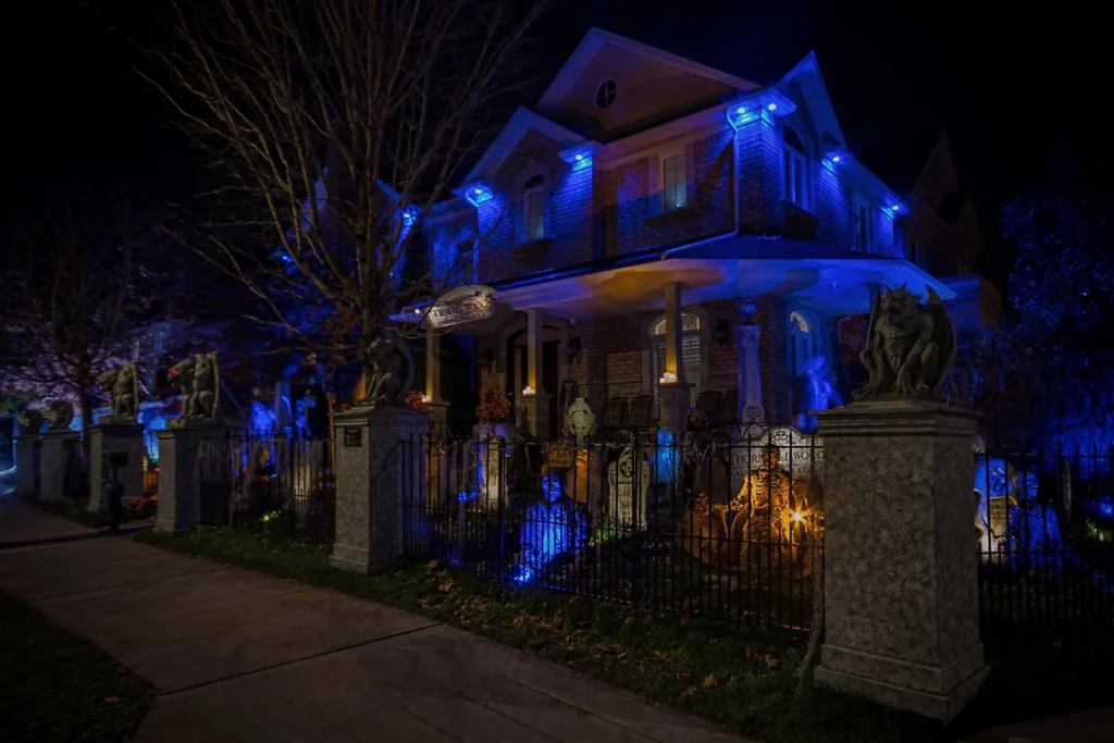 Thornhill Woods Haunted House lit in blue beside a fenced yard