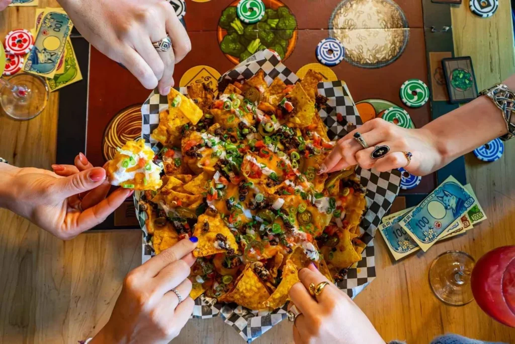 Friends sharing nachos around a board-game table at Snakes and Lattes