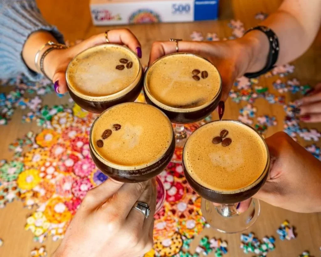 Several espresso martinis held above a board-game table