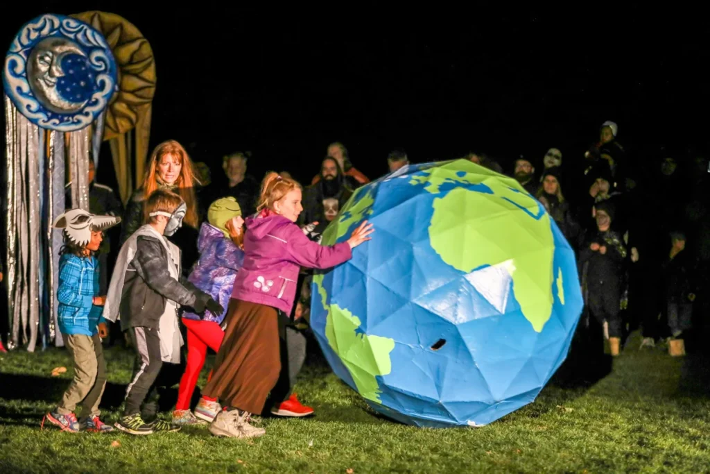 Puppeteers carrying a large Earth puppet during a Night of Dread performance