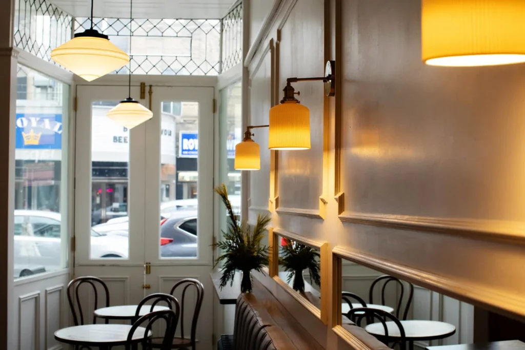 The glass front door and small tables inside Bar Pompette