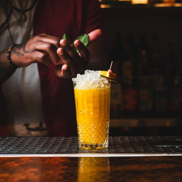 A bartender garnishing a tall yellow cocktail at Civil Liberties