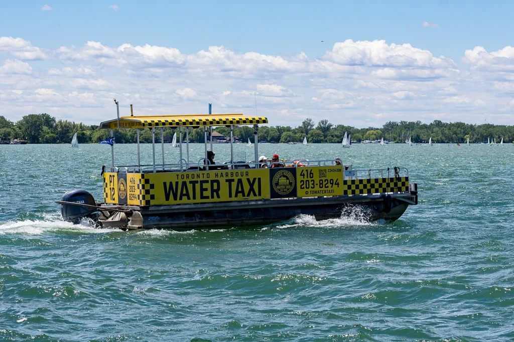 A yellow Toronto Harbour Water Taxi travelling beside Ward’s Island