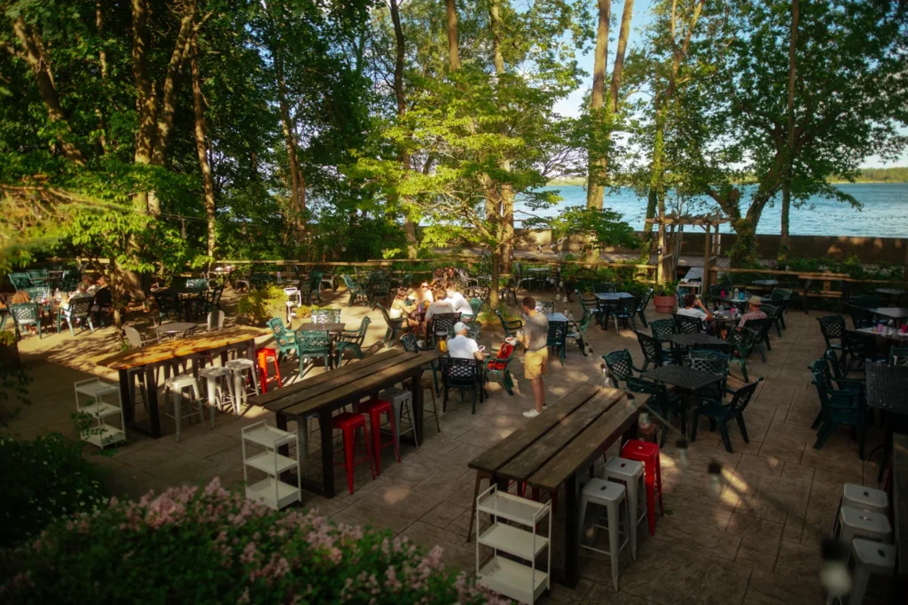 Tables and diners on the tree-shaded lakeside patio at the Riviera