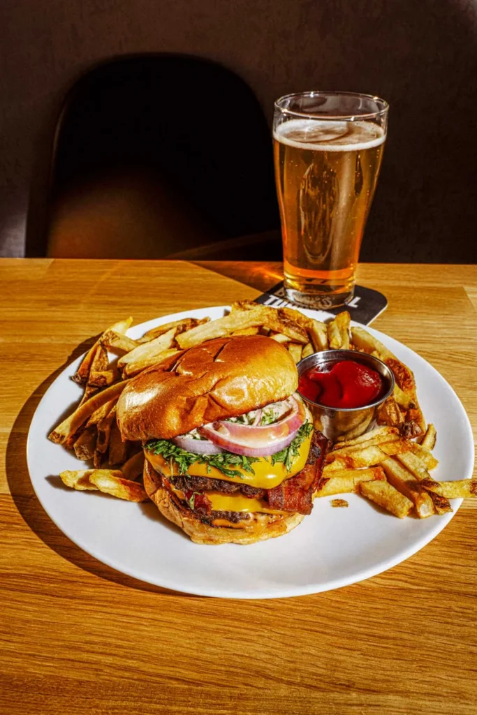 A burger with fries and a beer on a table at Real Sports