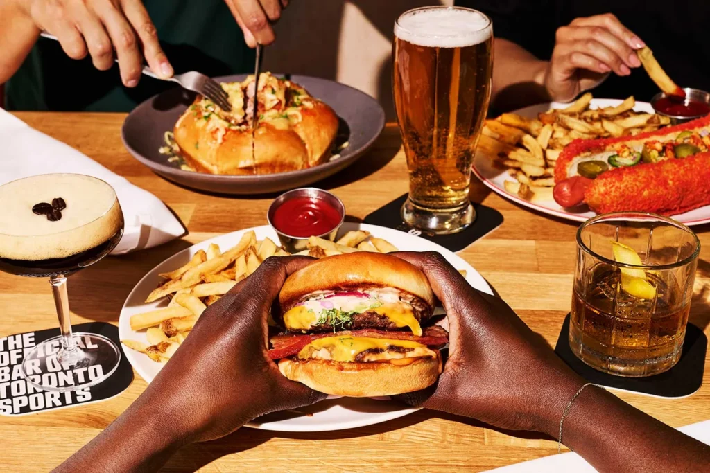 Friends sharing burgers, fries and drinks at Real Sports