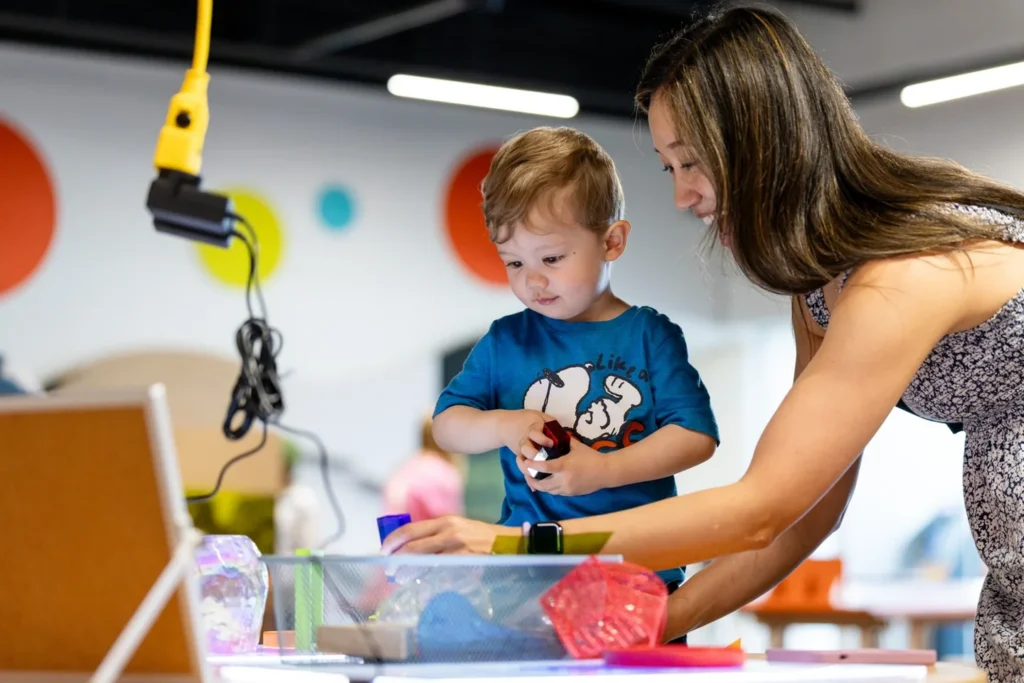 A woman helping a young child with a hands-on building activity