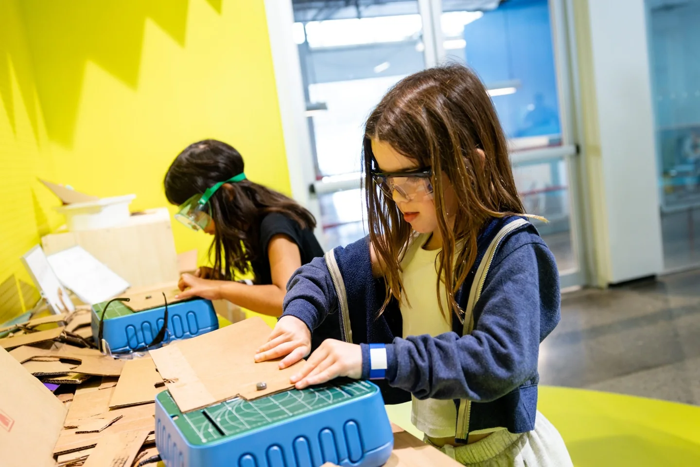 Two girls building cardboard projects at Innovation Station
