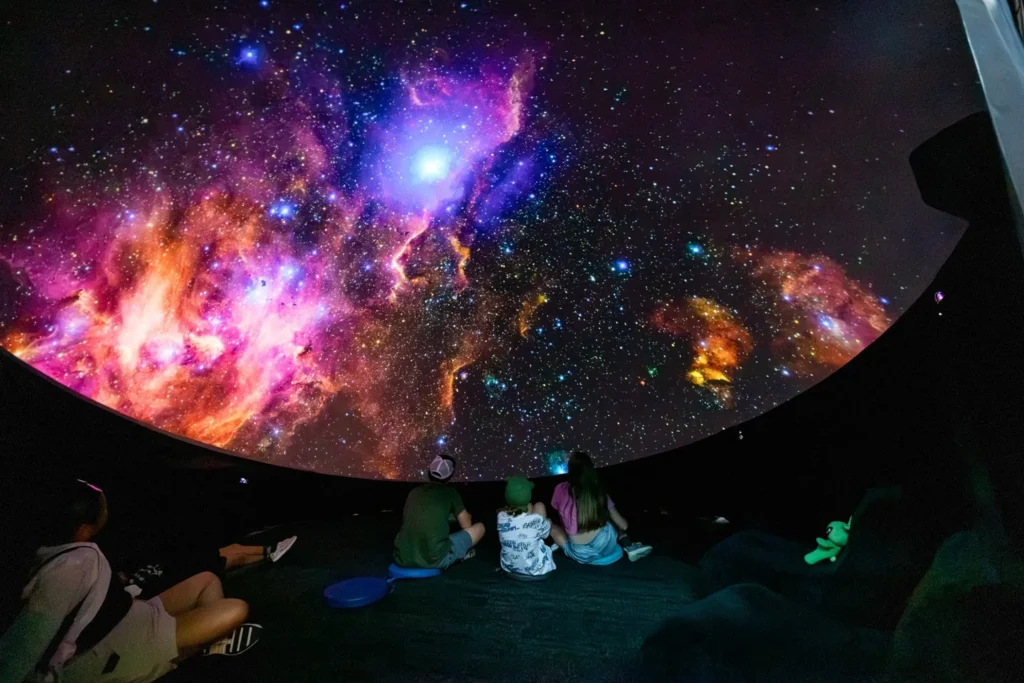 Children watching a large space projection inside a planetarium