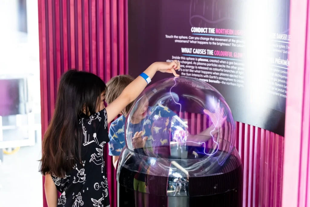 Children touching a glowing plasma ball at Space Deck