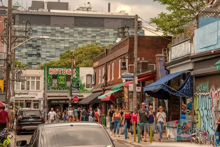 People walking past small shops on a Kensington Market street