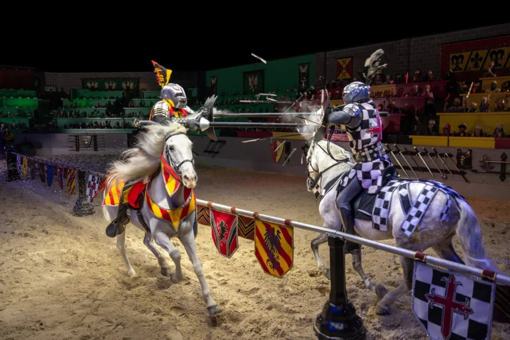Two costumed knights jousting on horseback in an indoor arena