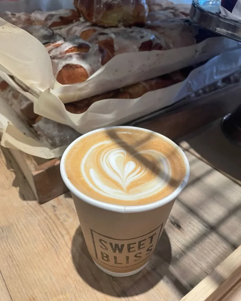 A Sweet Bliss coffee beside pastries