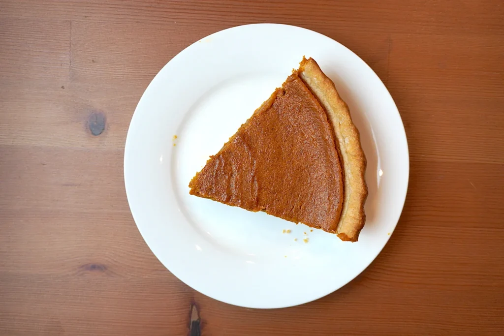 One slice of pumpkin pie on a small white plate