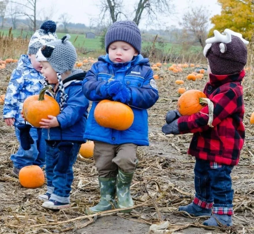 Three children carrying small pumpkins at Forsythe Family Farms