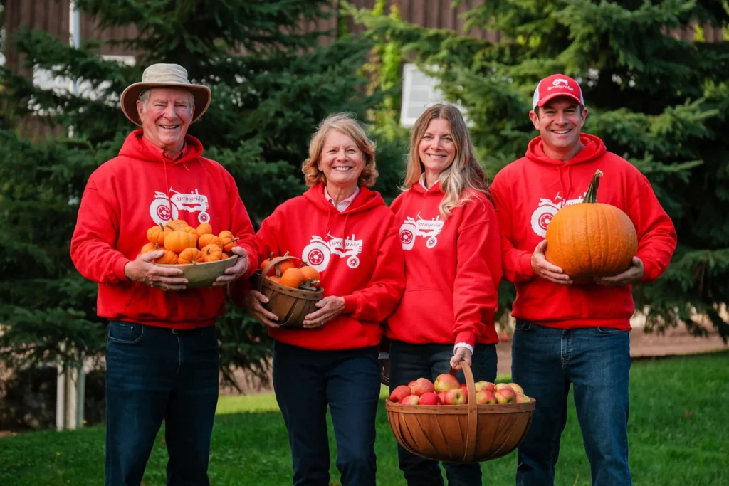 Four members of the Springridge farm family holding pumpkins and gourds