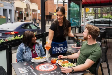 A server and guests on the Café Diplomatico patio on College Street