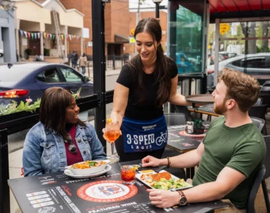 A server and guests on the Café Diplomatico patio on College Street