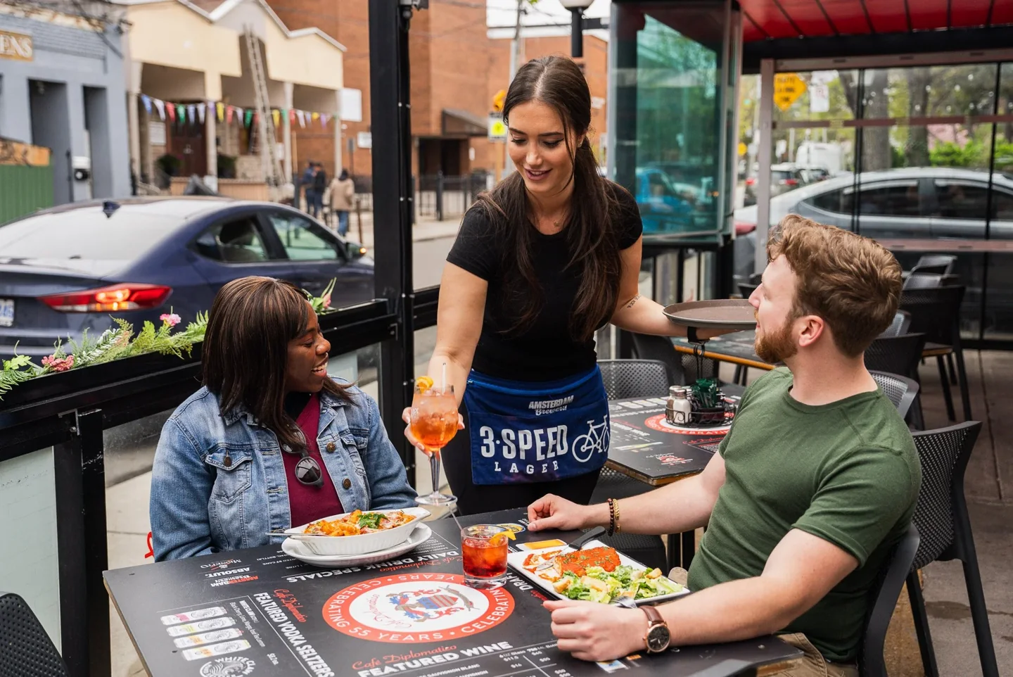 A server and guests on the Café Diplomatico patio on College Street