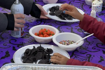 Hands decorating cupcakes at Riverside Halloween Fest