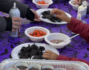 Hands decorating cupcakes at Riverside Halloween Fest
