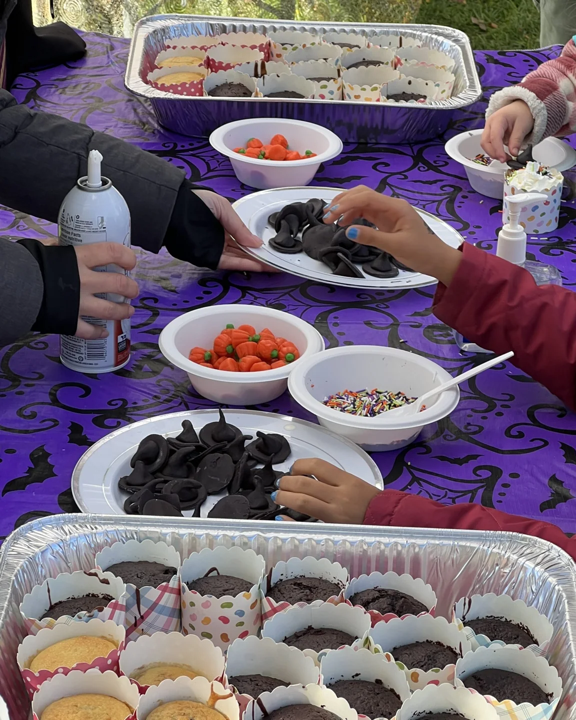 Hands decorating cupcakes at Riverside Halloween Fest