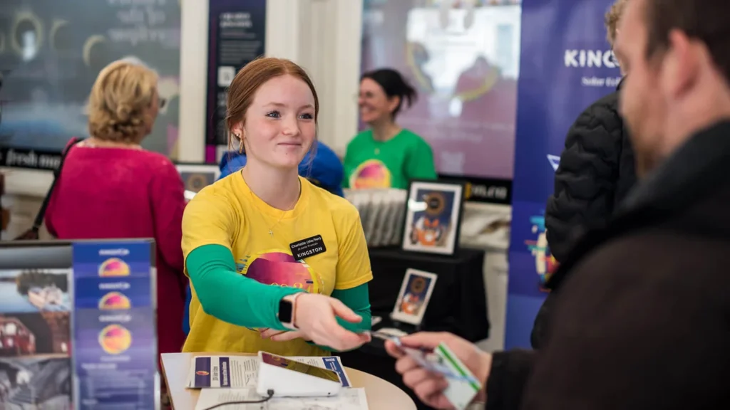Visitor centre staff member helping a guest at a counter in Kingston