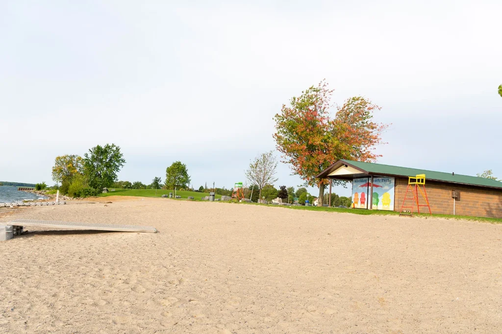 Morrisburg beach with trees and a building behind the sand