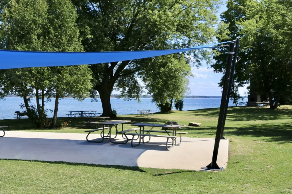Picnic tables on pavement under a shade canopy at Browns Bay