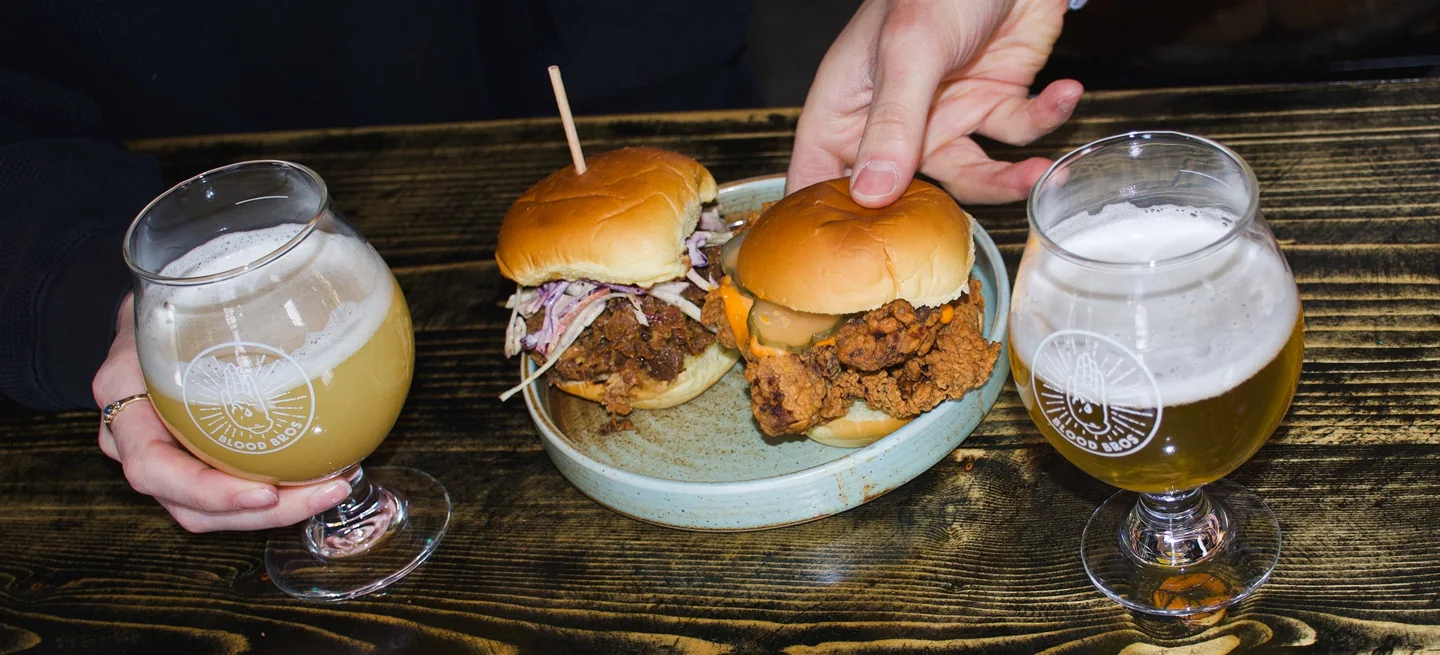 Two sandwiches and glasses of beer on a wooden table at Blood Brothers