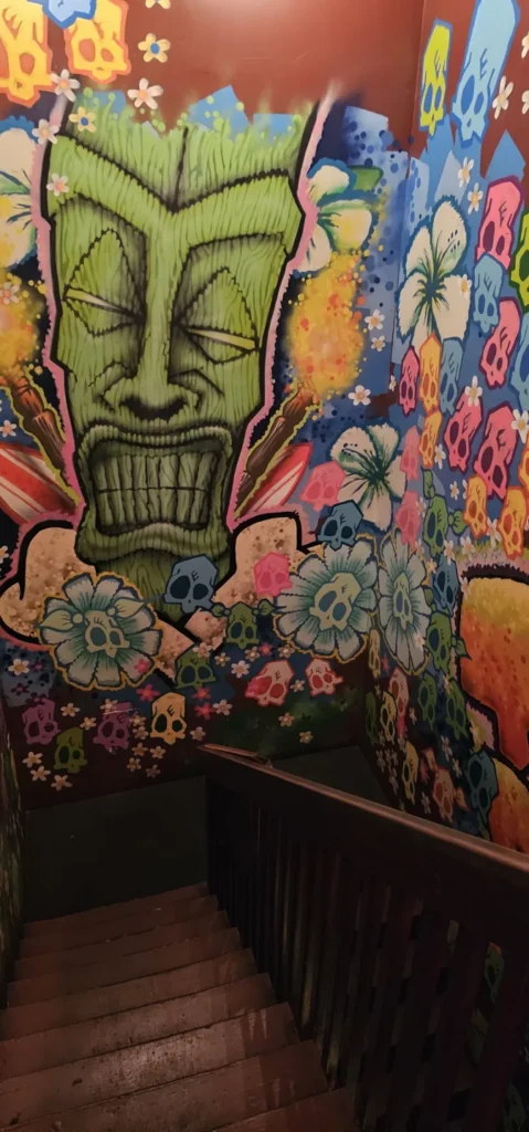 A stairway beside a colourful tiki mural at Bovine Sex Club
