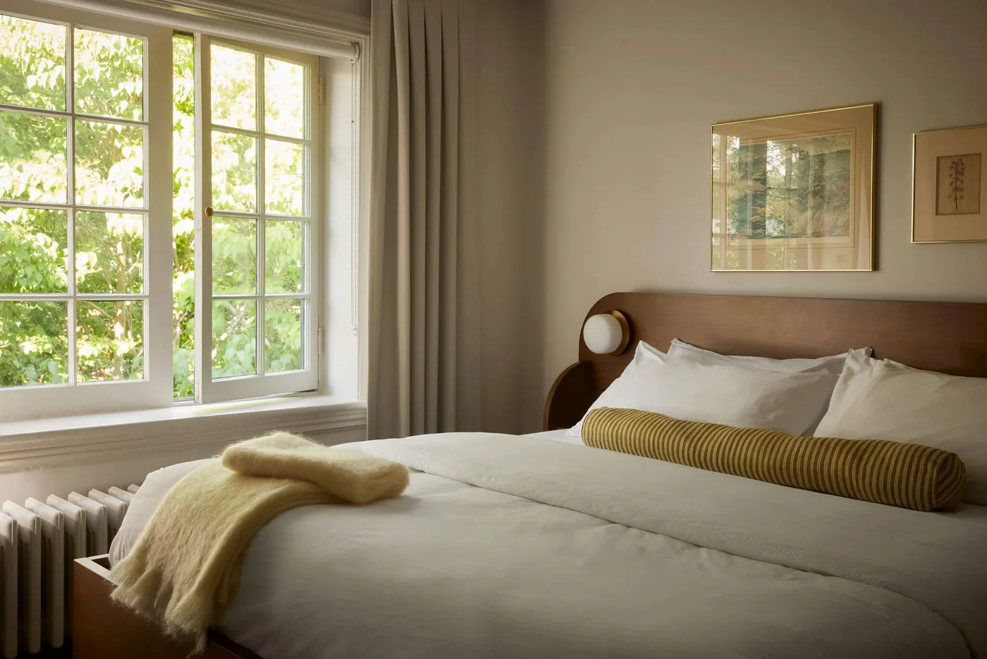 Cream bedding and green cushions beside a large window at Belvedere Hotel