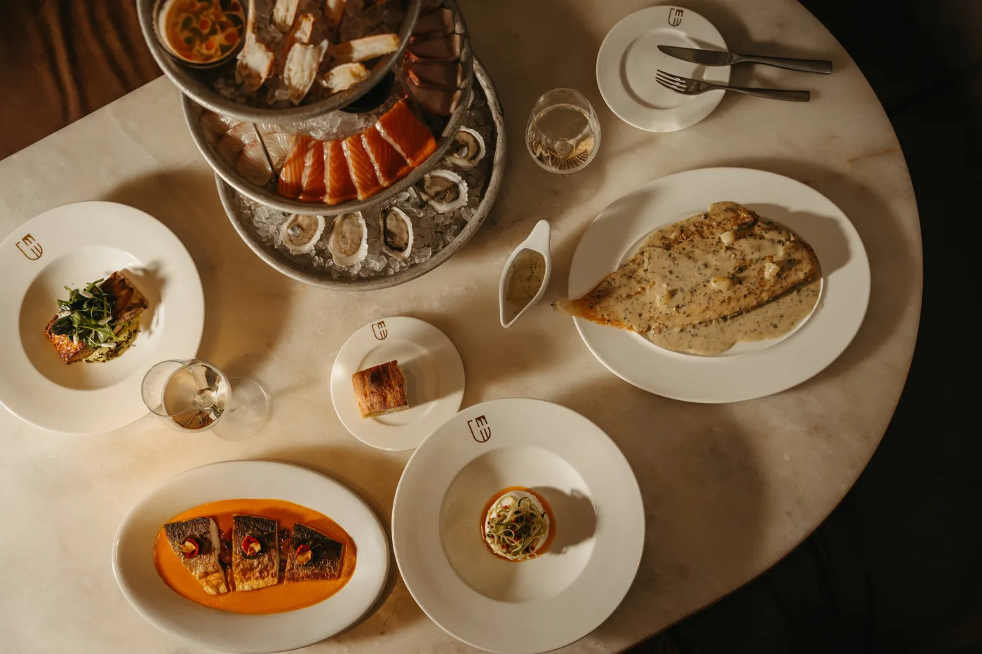 A hotel dining table with a seafood platter, bread and several dishes
