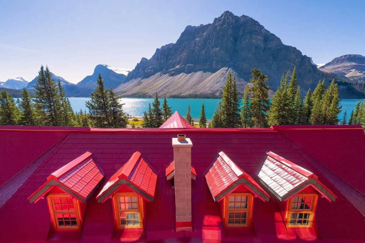 The red roof of the Lodge at Bow Lake with turquoise water and mountains beyond