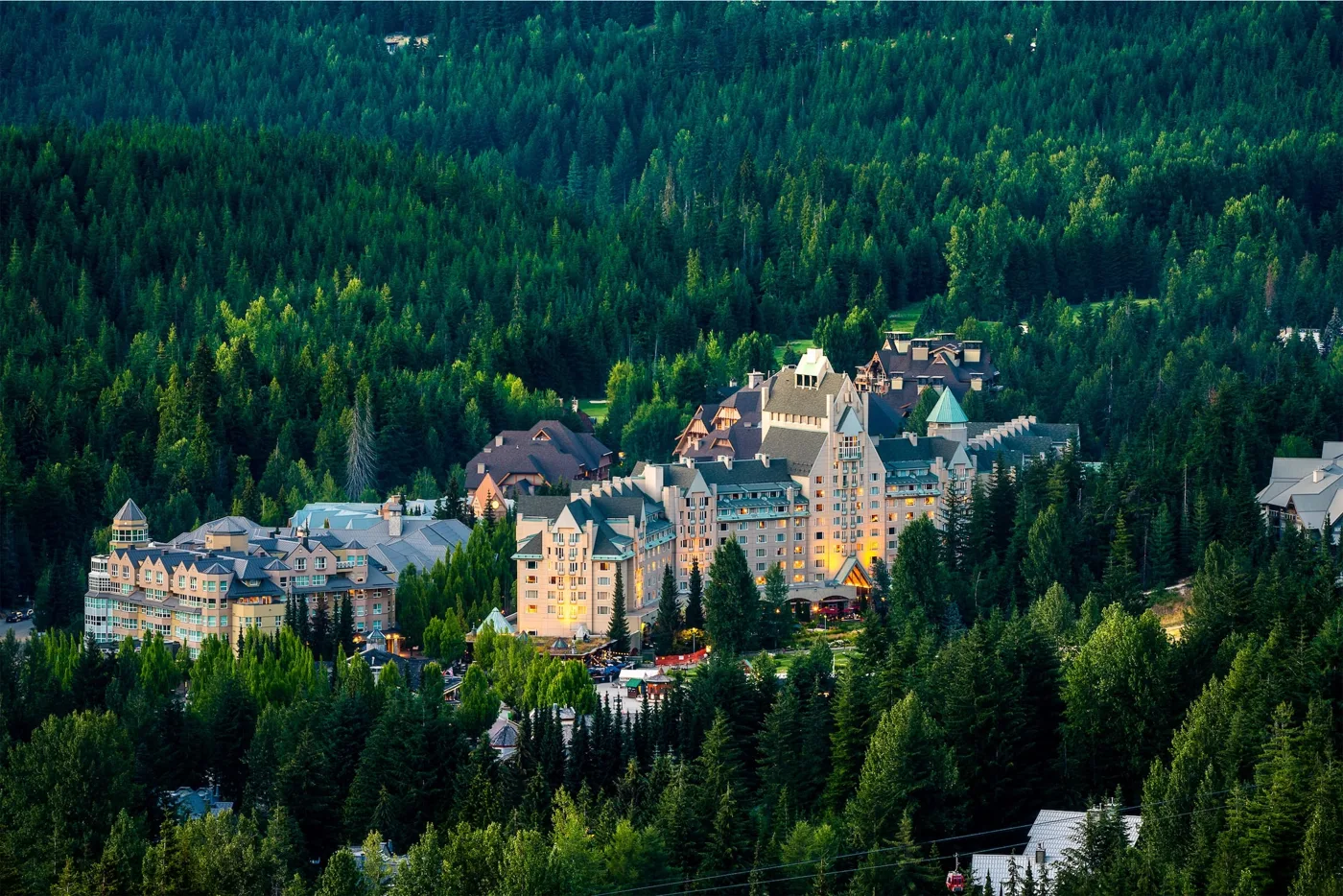 Fairmont Chateau Whistler surrounded by green forest below the mountains