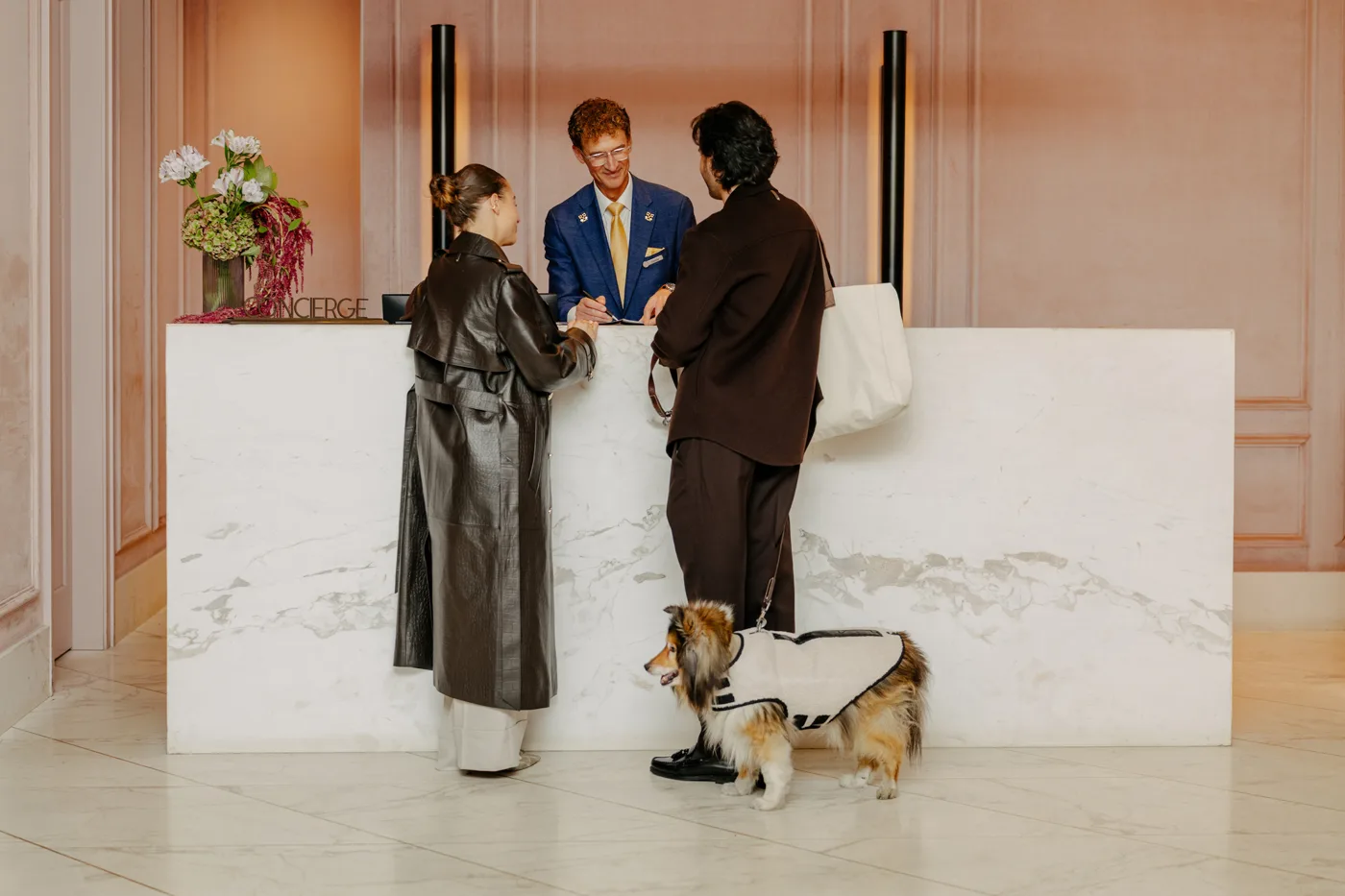 Guests with two dogs speaking to a Four Seasons Montreal staff member at a counter