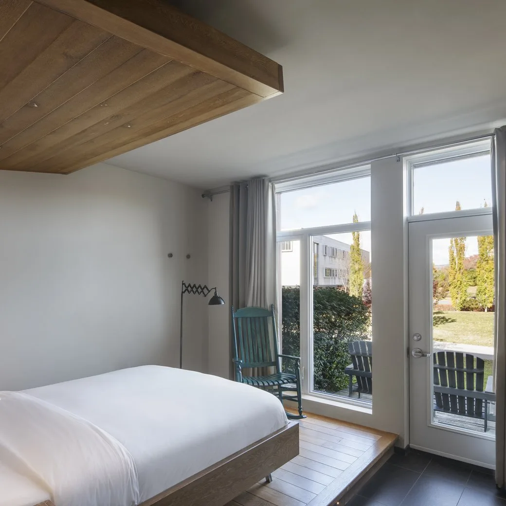 A bright guest room with a pale wood ceiling and glass doors at Le Germain Charlevoix