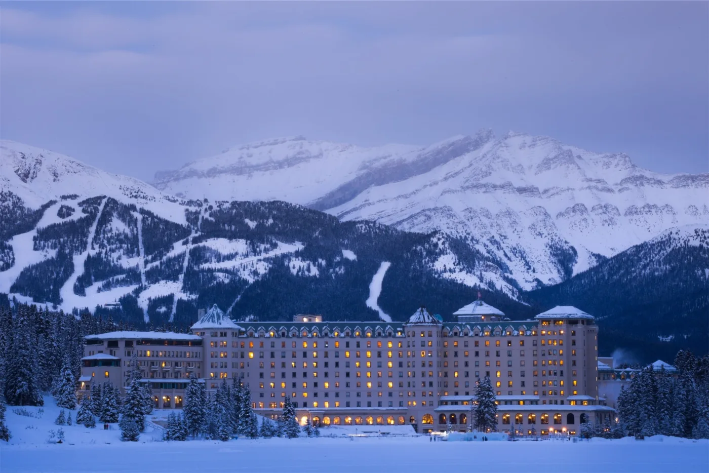 Fairmont Chateau Lake Louise below snow-covered mountains in winter