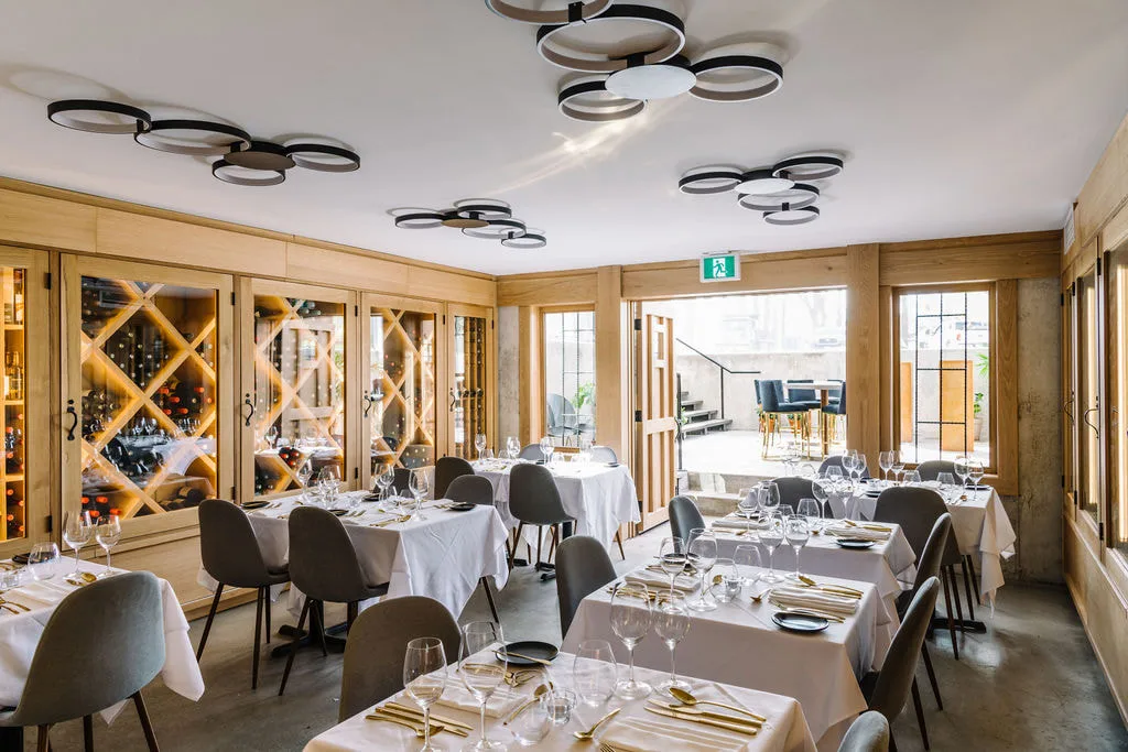 White chairs and set tables beside wine storage in Merrill House's dining space
