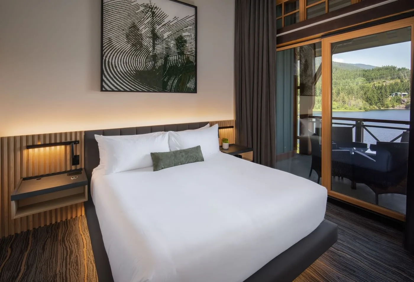 A king bed beside an open balcony overlooking Nita Lake