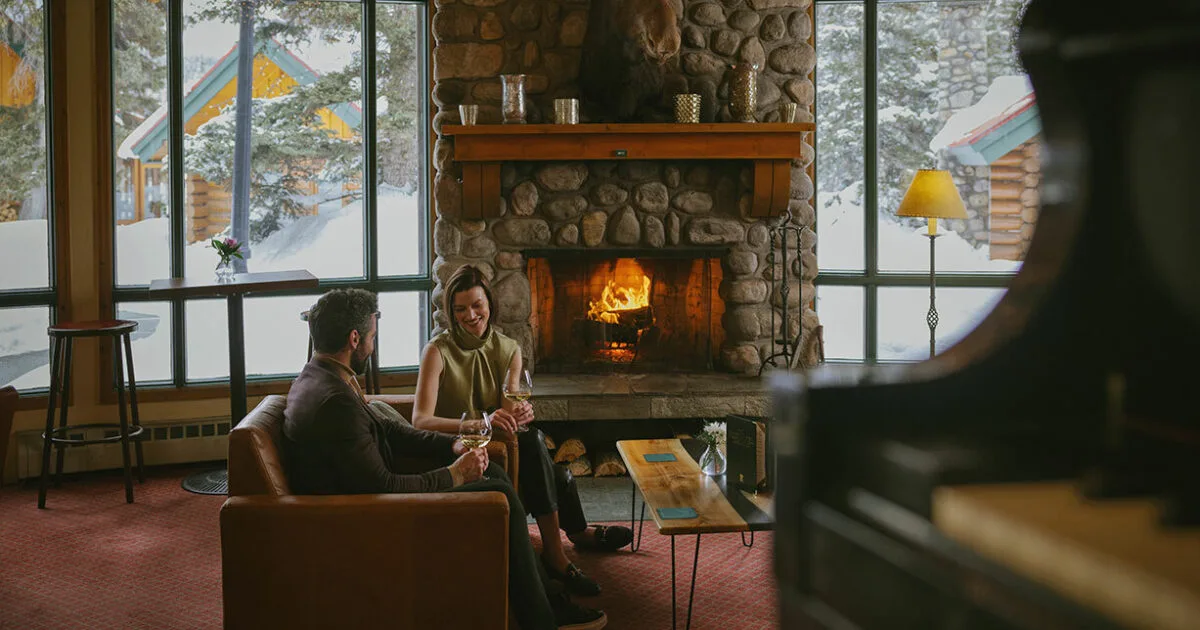 Guests sitting by a stone fireplace at Post Hotel and Spa
