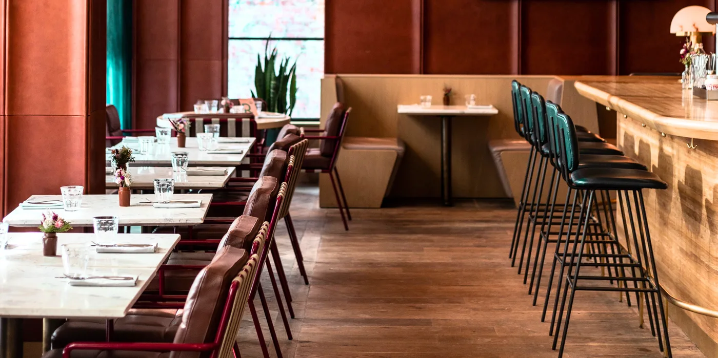 Tables and green upholstered seats in the Royal Hotel's warm dining space