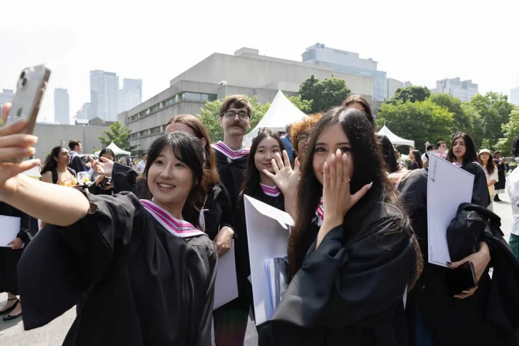 University of Toronto graduates taking a selfie outside Convocation Hall