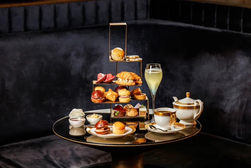 A tiered stand of savouries and sweets beside a teapot at CLOCKWORK