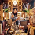 Two women sharing afternoon tea beneath the clock at Fairmont Royal York